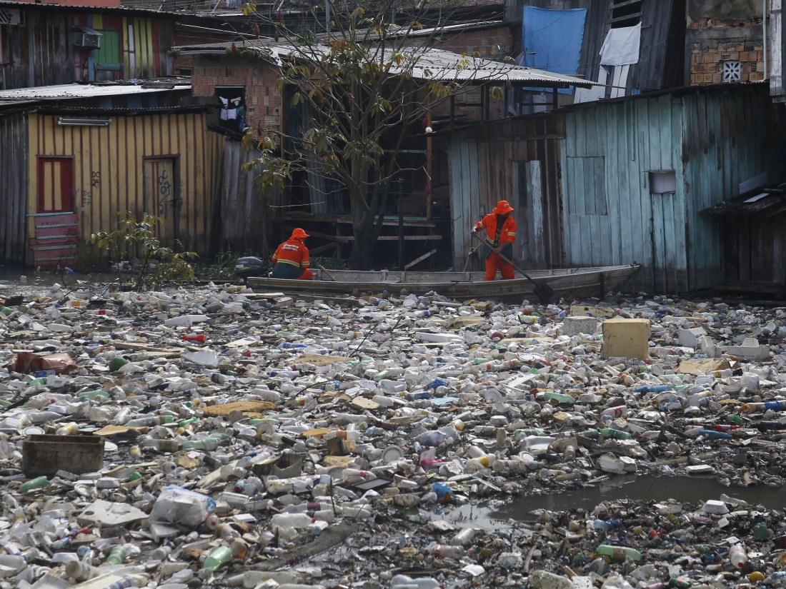 Trabalhadores removem lixo que flutua no Rio Negro, em Manaus, Brasil.