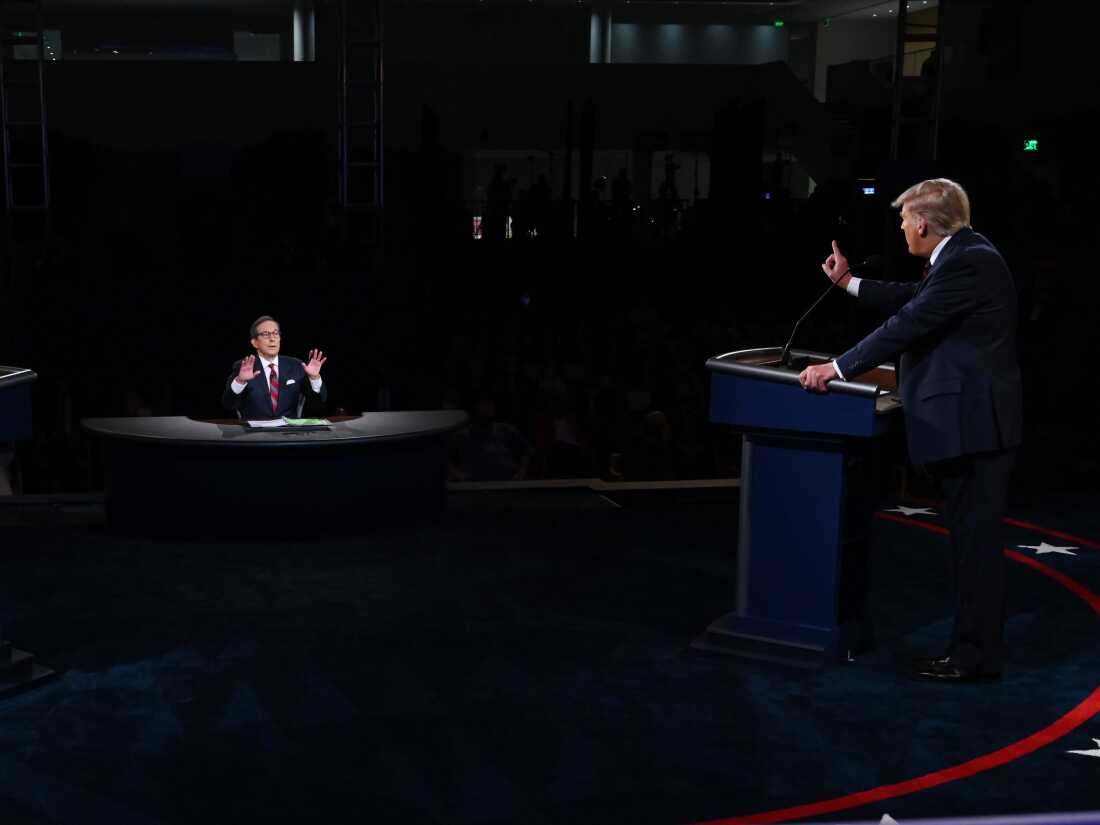 Chris Wallace, com as mãos para cima, modera um debate entre Trump e Biden no palco.